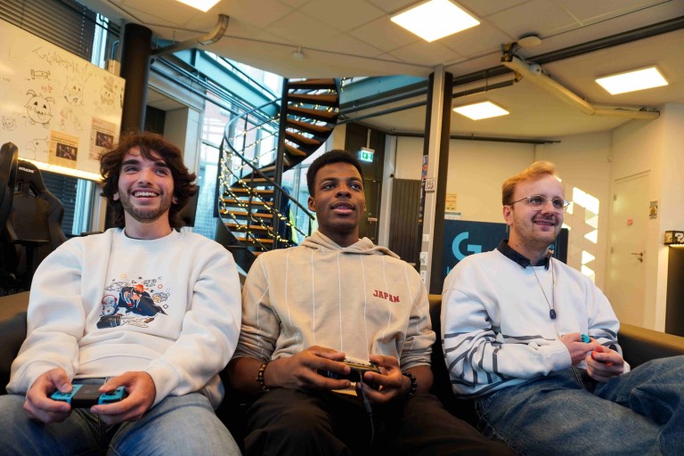 Drie studenten spelen samen een videogame