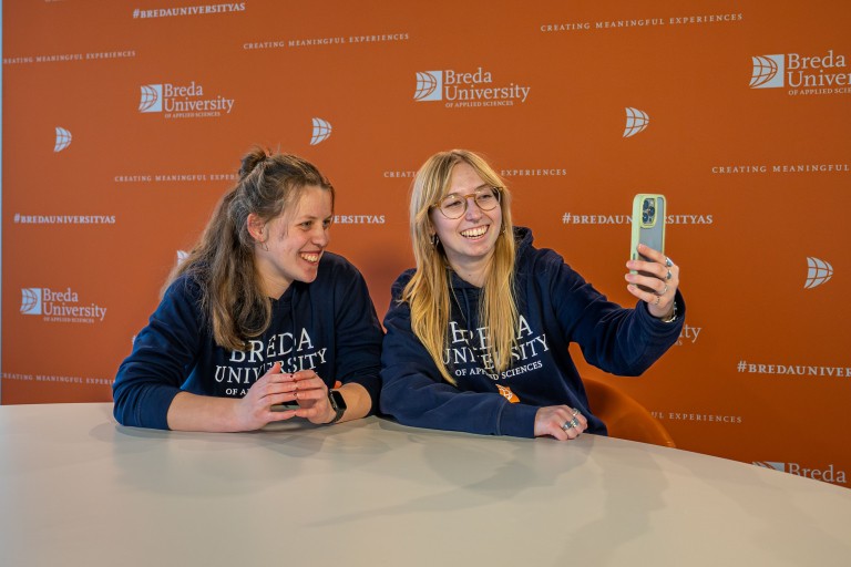 Twee student ambassadors lachen voor een telefoon
