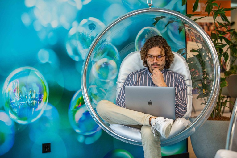 Student in een hangstoel werkt op een laptop