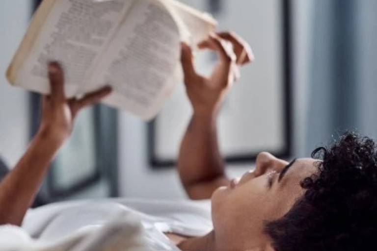Een jongen leest een boek in bed