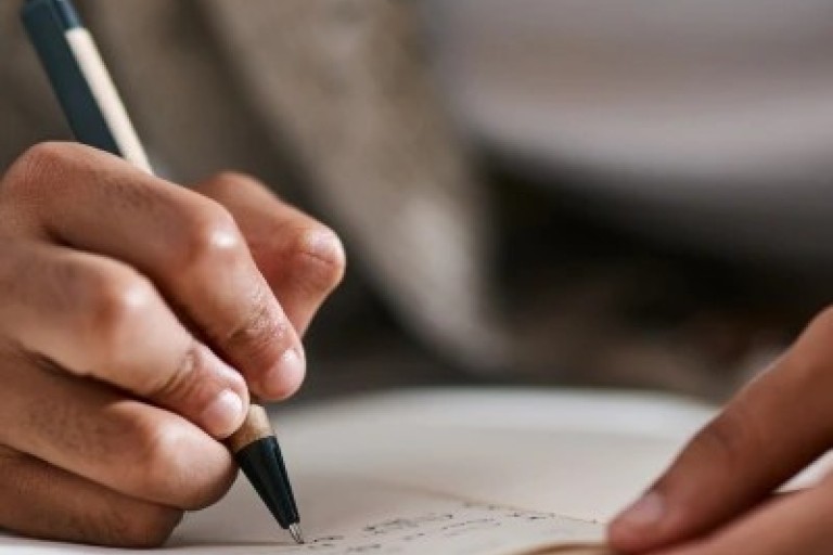 Iemand schrijft met een pen op papier