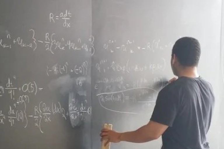Een jongen schrijft wiskundige formules op een krijtbord