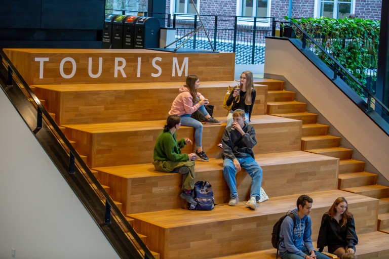 Studenten zitten te kletsen op een trap binnen het buas gebouw