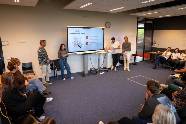 4 mensen geven een presentatie aan studenten