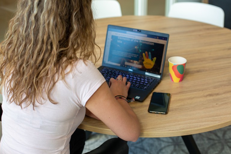 Student zit aan tafel achter haar laptop te werken