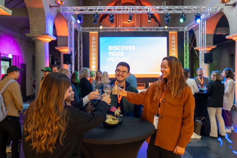Mensen op een event proosten met elkaar aan een statafel 