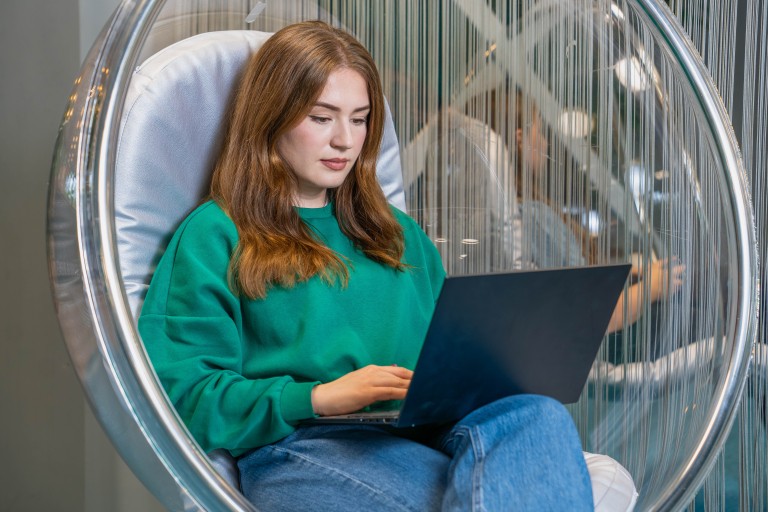 Student in een hangstoel met laptop op schoot