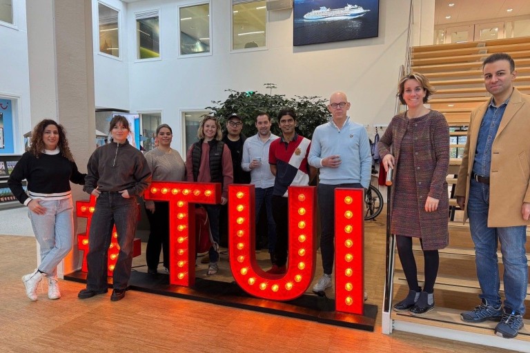 Een groep mensen staat bij grote neon letters van TUI