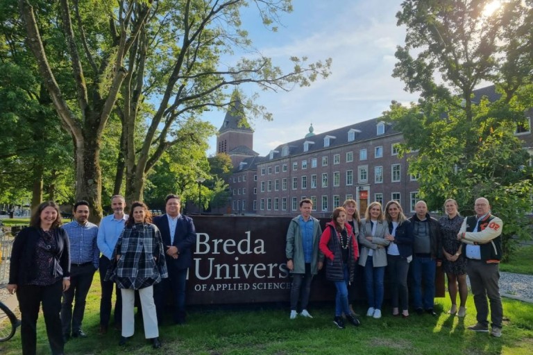 Een groep mensen voor het BUas bord dat op de campus staat