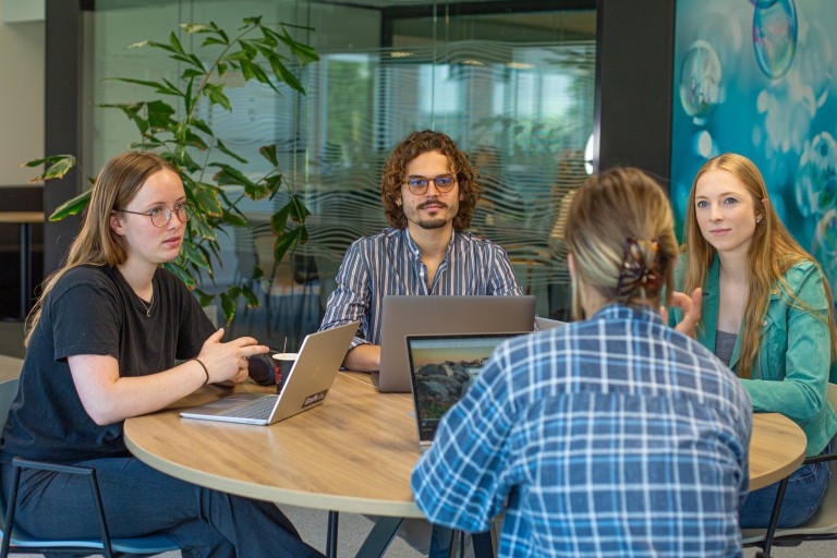Vier studenten zitten aan tafel