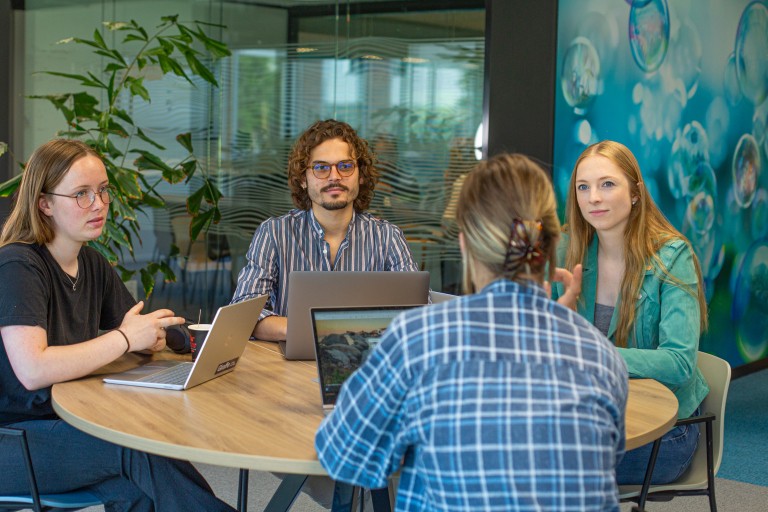 Vier studenten zitten aan tafel