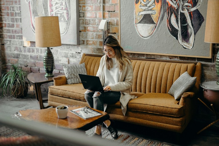 Student met laptop zit thuis op de bank