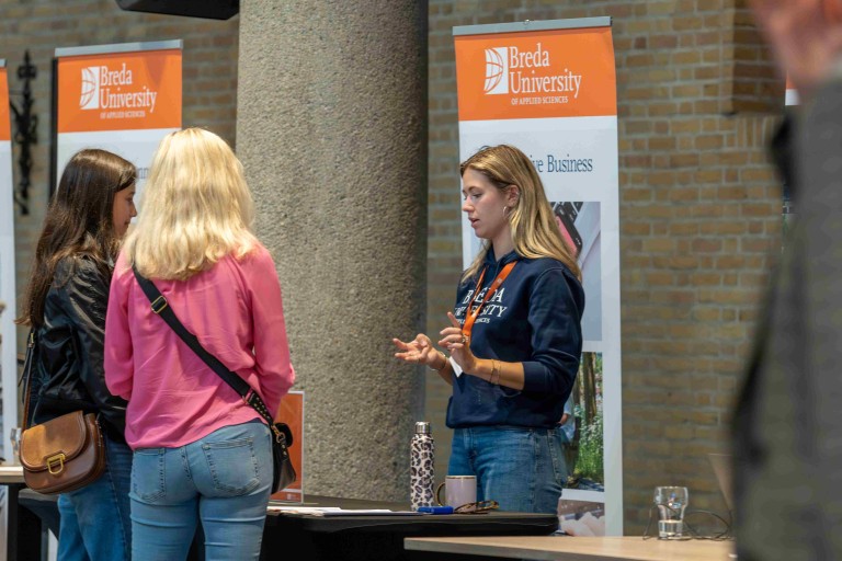 Moeder en dochter in gesprek met een student tijdens open dag