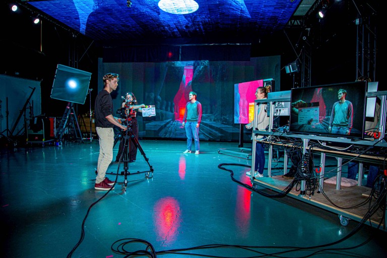 Filmset met acteur voor LED-videowall, gefilmd door crew met camera en klapperbord.