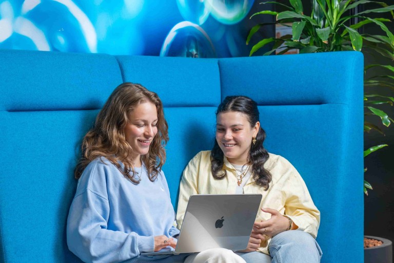 two students on a bench with a laptop