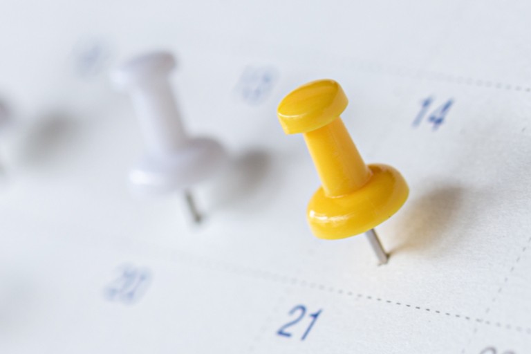 Witte en gele punaises zijn op een kalender geprikt 