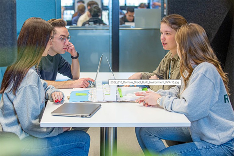 Vier studenten aan een tafel werken samen aan een project