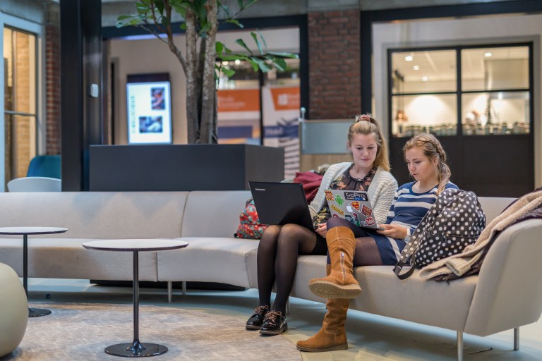 Twee studenten werken op laptops op een bank