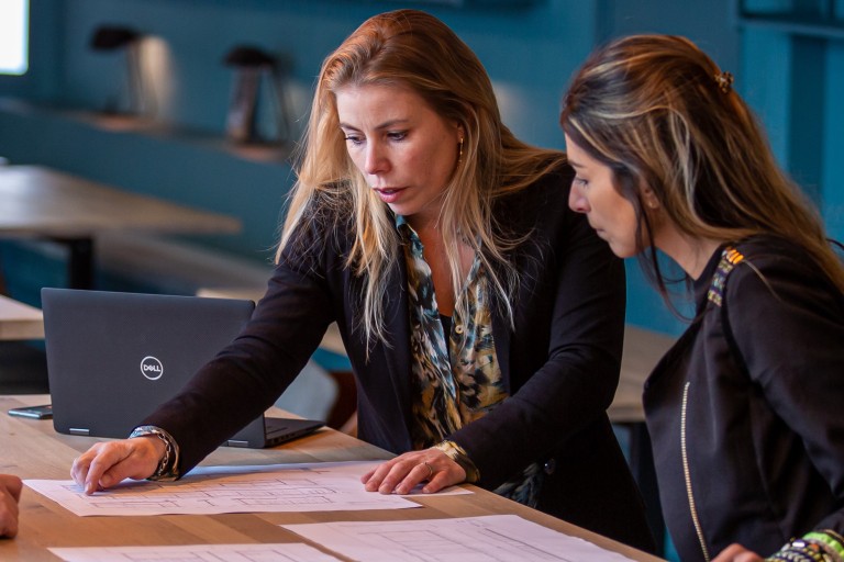 Drie vrouwen bespreken documenten op een tafel 