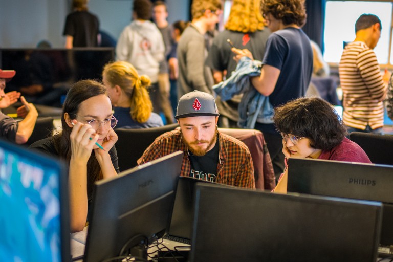 Drie studenten kijken samen op een computer