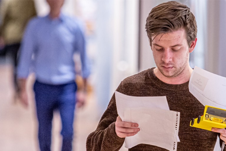 Een man kijkt naar papieren in zijn hand