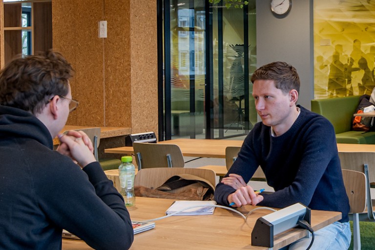 Studenten werken in een ruimte met tafels, stoelen en banken