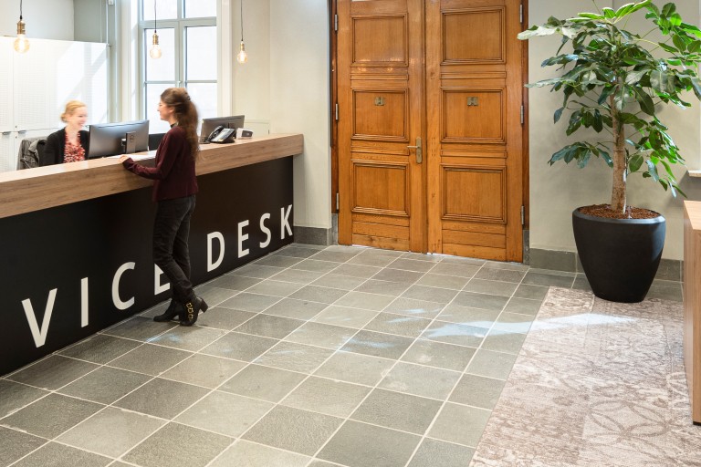 Een vrouw vraagt iets bij de balie van de service desk