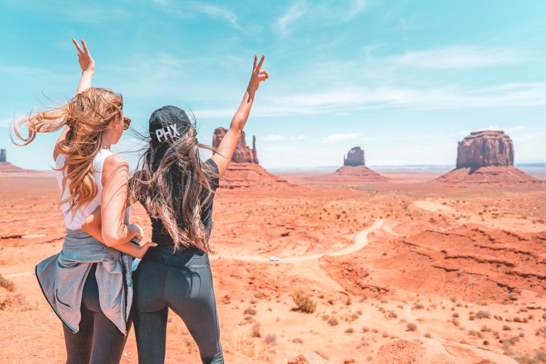 Twee toeristen poseren in een woestijn met rotsen