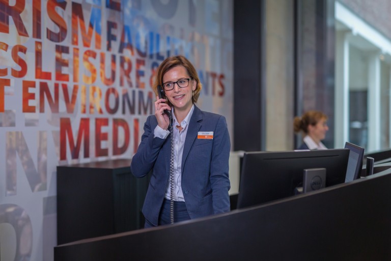 Vrouw neemt de telefoon op bij de BUas receptie