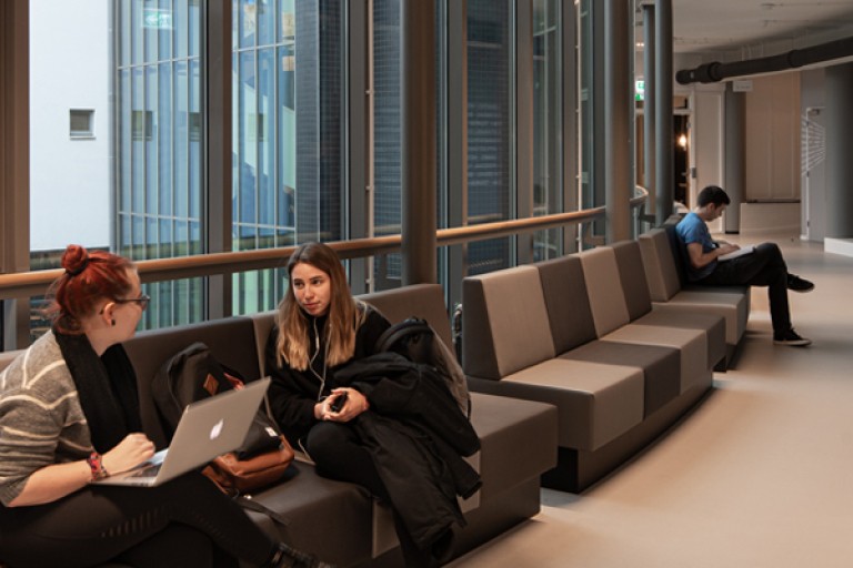 Studenten praten op banken in een gang