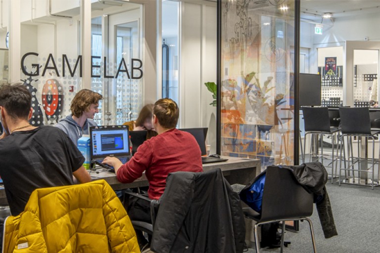 Studenten werken op hun laptops aan een tafel