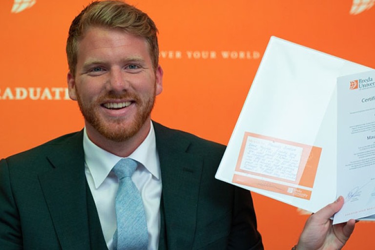 Een student houdt een BUas diploma vast