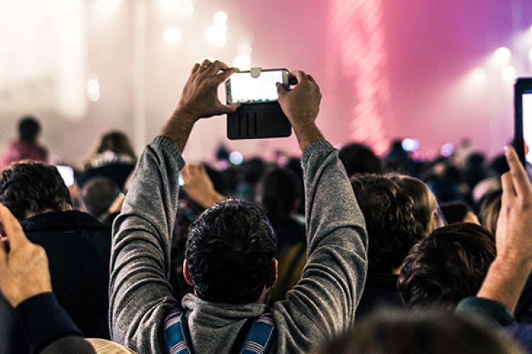 Audience holding cameras at a large concert, an event that could be involved in during the Master Strategic Events Management.