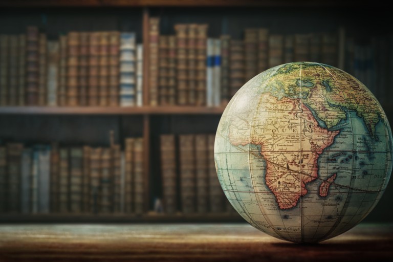 Een wereldbol ligt op een tafel voor een boekenkast