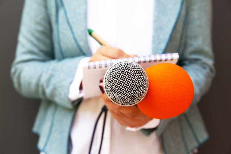 Iemand met een microfoon en notitieblok