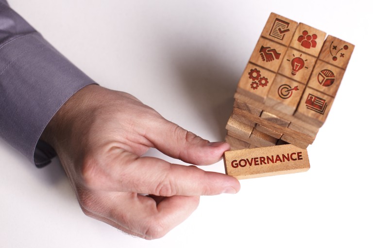 Een hand houdt een bordje met de tekst Governance vast