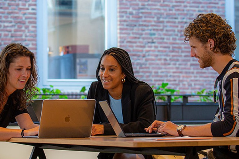 Studenten lachend achter een computer