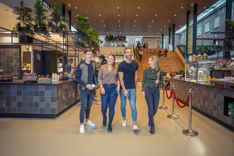 Vier studenten wandelen in het BUas Horizon gebouw
