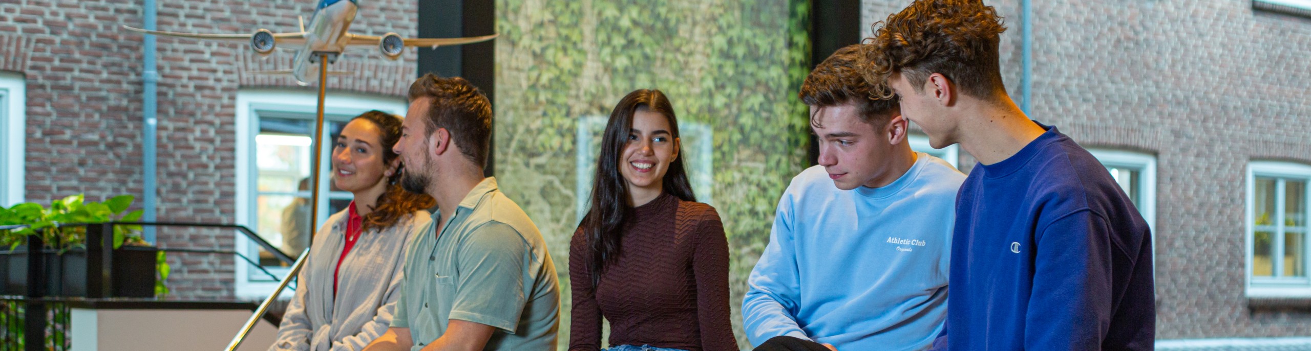 Vijf studenten zitten op een houten blok