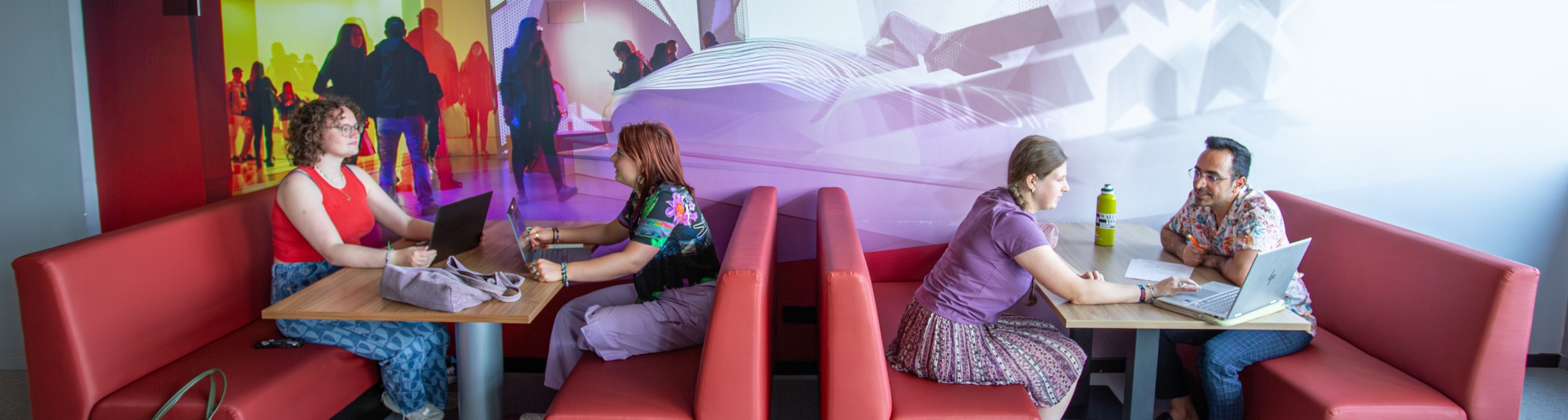 Studenten werken samen met laptops op roze banken