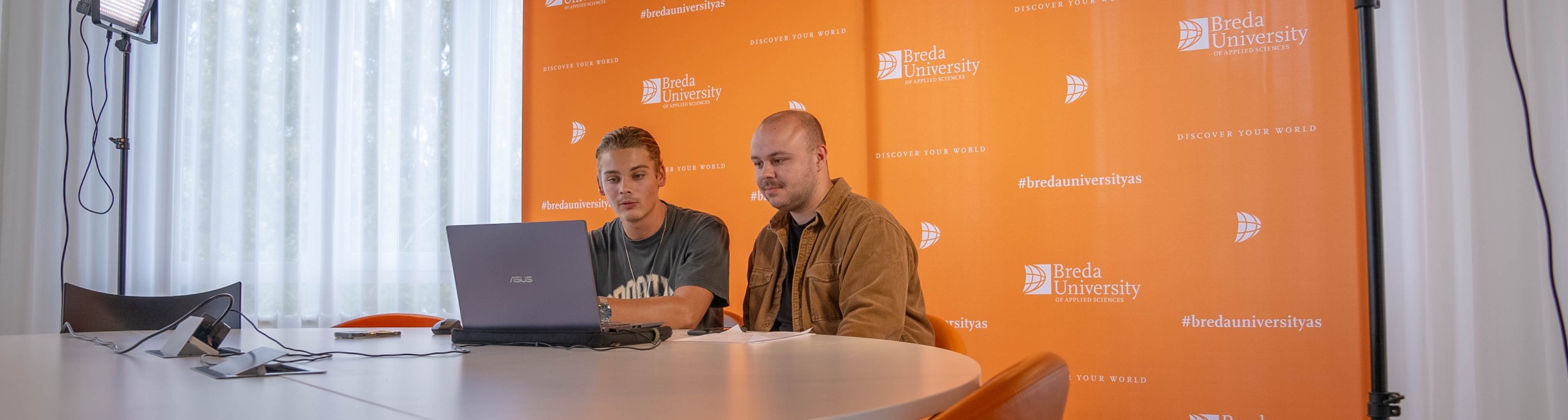 Twee studenten zitten voor een laptop voor de online open dag