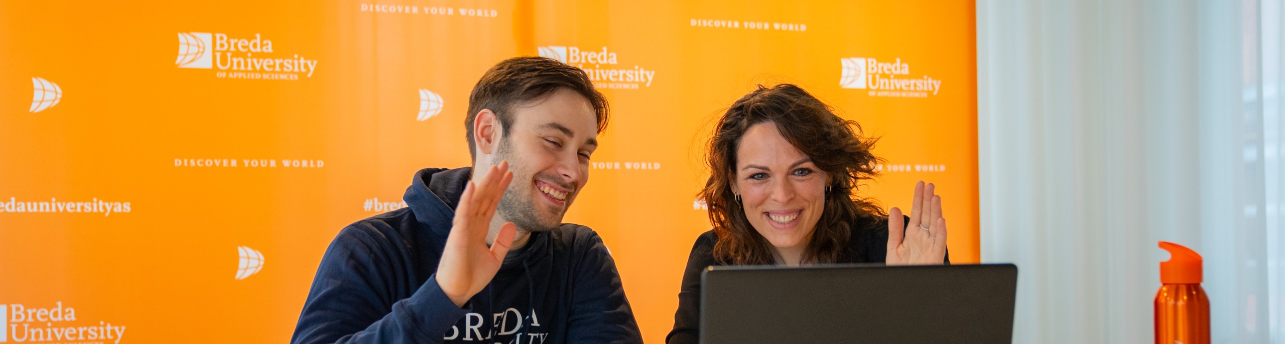 Een docent en student zwaaien naar een laptop