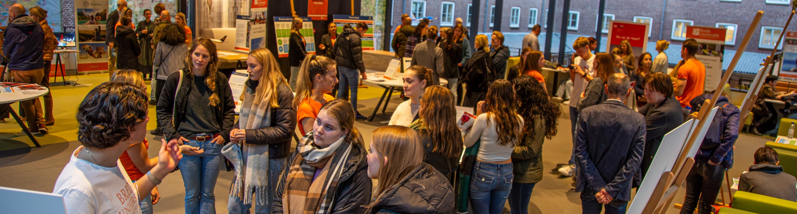 Studenten en docenten praten met bezoekers op de open dag