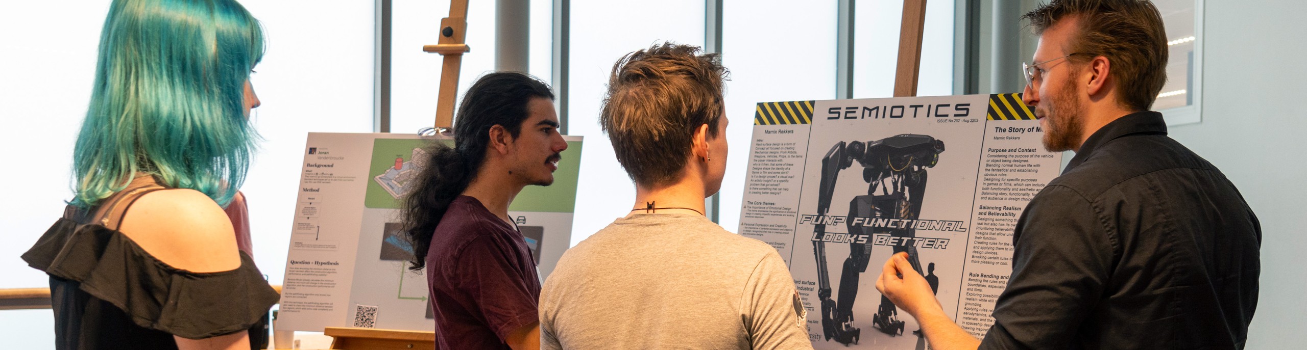 Een docent en drie studenten bekijken een project op een ezel