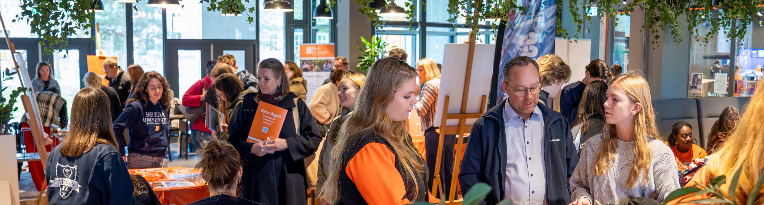 Studenten en docenten praten met bezoekers op de open dag