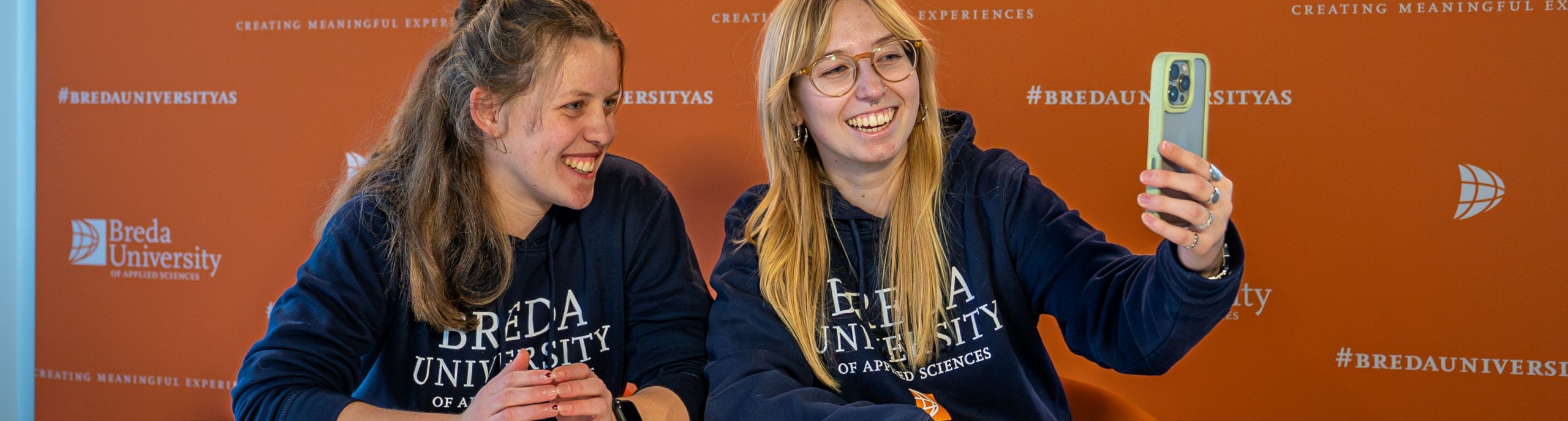 Twee student ambassadors lachen voor een telefoon