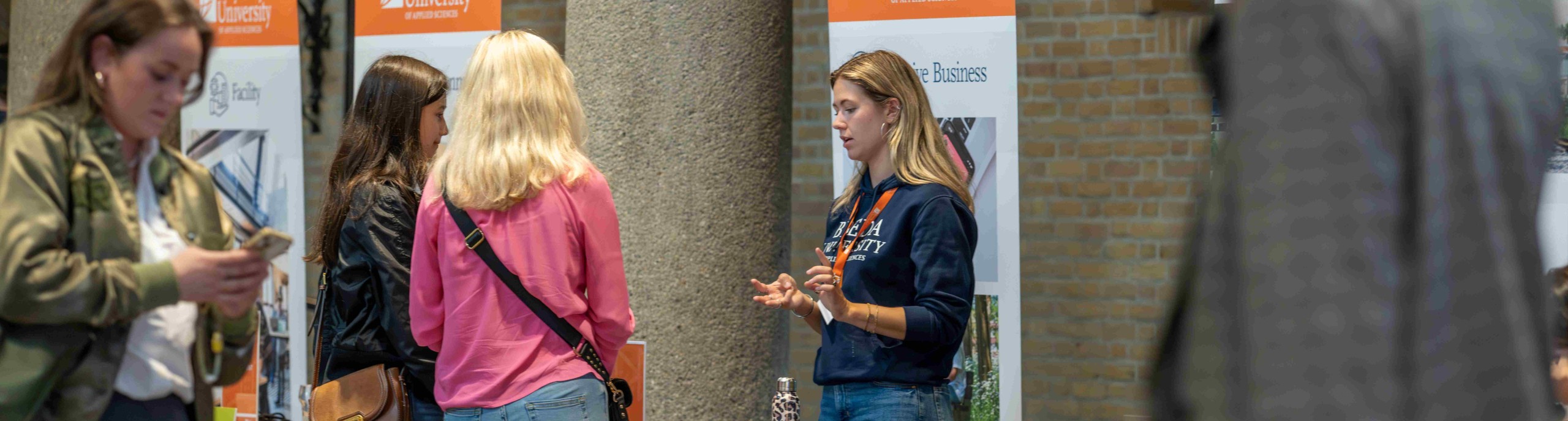 Moeder en dochter in gesprek met een student tijdens open dag