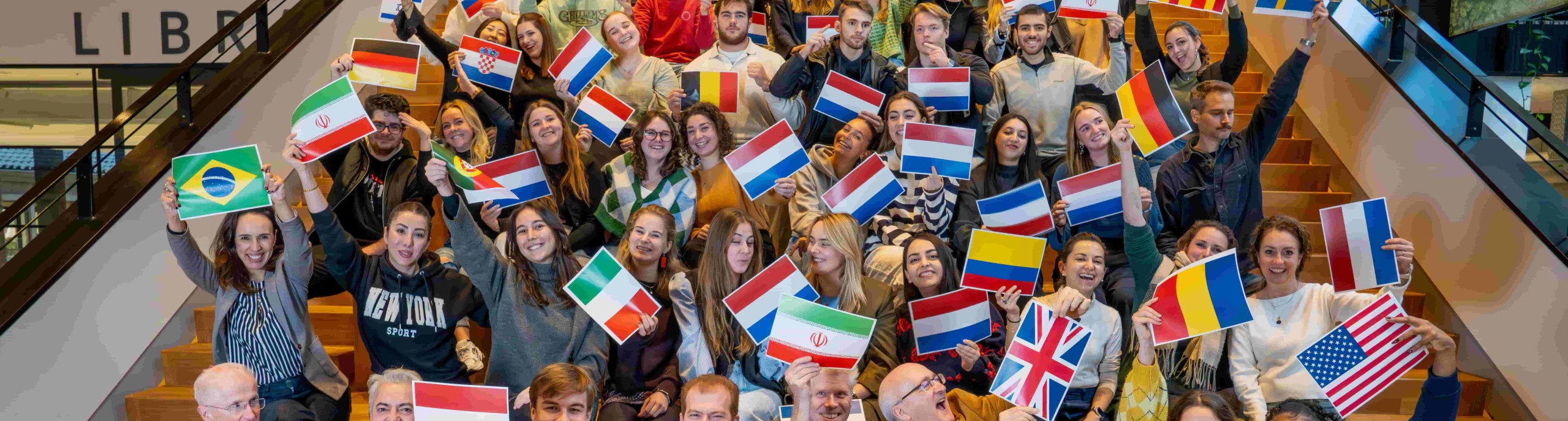 students with flags from different countries sitting on stairs