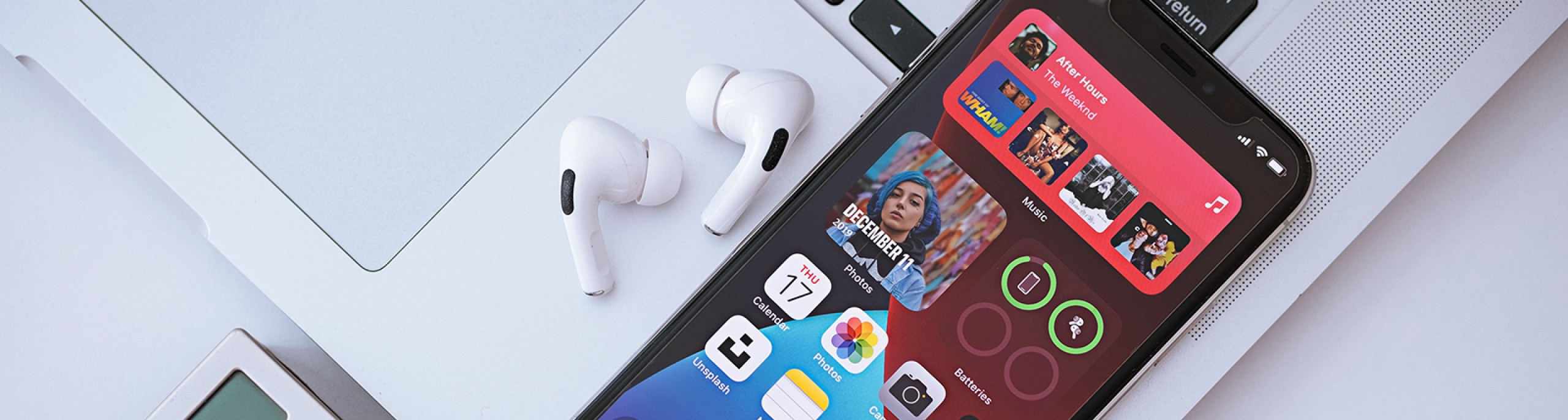 Een telefoon, laptop, camera en AirPods liggen op een tafel 