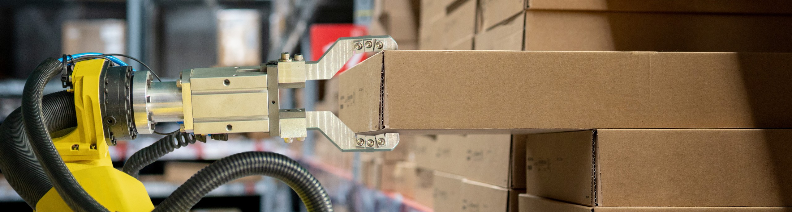 Een robot grijpt een kartonnen doos uit een stapel